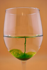 Colored water dropping into a wine glass filled with water.