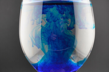 Colored water dropping into a wine glass filled with water.