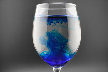 Colored water dropping into a wine glass filled with water.