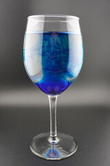 Colored water dropping into a wine glass filled with water.
