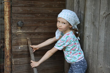 little girl in a village is holding a stick. girl is working in countryside. village atmosphere