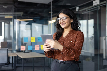 Successful businesswoman inside the office using tablet computer. Woman satisfied with the results...