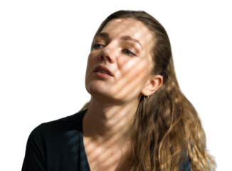Portrait of a young beautiful girl in a room on a background of a gray wall with shadows, natural light from the window.