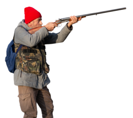 Mature hunter man holding a shotgun and walking through a field