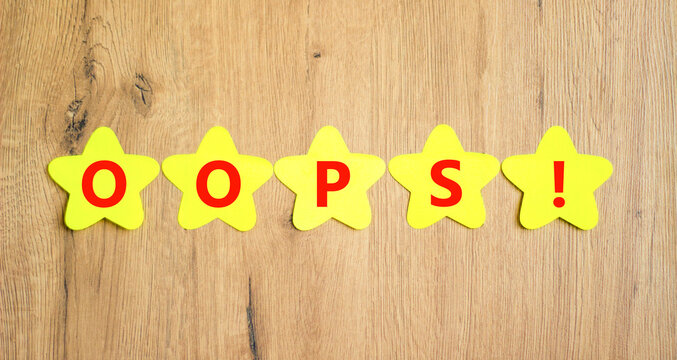 Oops symbol. Concept word Oops on beautiful yellow paper stars. Beautiful wooden table wooden background. Business lifestyle oops concept. Copy space.
