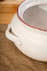 White ceramics dish with handles and lid for baking stands on kitchen table