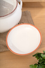 White ceramics dish with handles and lid for baking stands on kitchen table