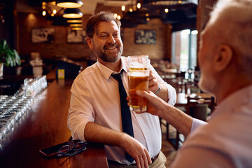 Happy businessmen toasting with beer while gathering for drink after work.