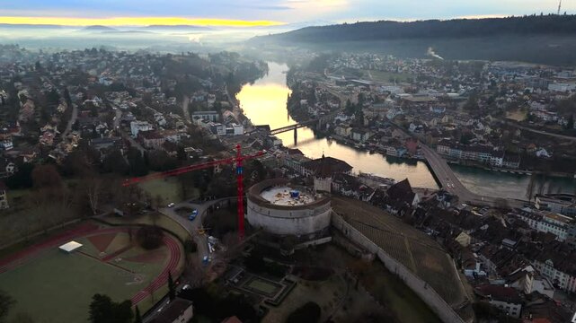 Breathtaking aerial view of Schaffhausen, Switzerland, featuring iconic Munot fortress, Rhine River, and historic bridges. Morning light casts golden glow over charming old town and scenic landscapes