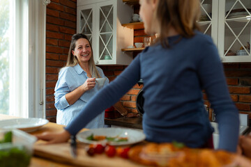Mother and daughter enjoying a pleasant morning together in their kitchen, sharing a conversation and a meal, creating a warm and intimate family atmosphere