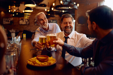 Cheerful businessmen toasting while gathering for beer in pub.