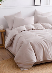 Bedroom with a double bed, fluffy down comforter and four pillows. Side view vertical photo