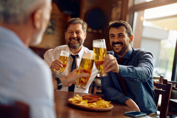 Happy business colleagues toasting while drinking beer in pub after work.