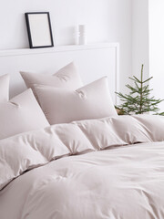 Obraz premium Scandinavian style bedroom with a double bed, fluffy down comforter and four pillows. Close-up side view vertical photo.