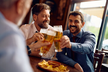 Happy businessmen toasting while gathering after work in pub.