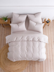 Double bed with a fluffy duvet in a beige duvet cover and four pillows. Top view photo