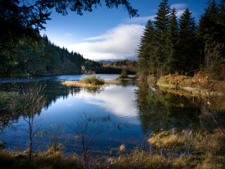 Obraz premium Reflets d’un ciel bleu sur un loch entouré de forêts, Écosse