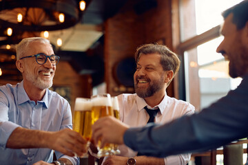 Happy businessmen toasting with beer in pub.