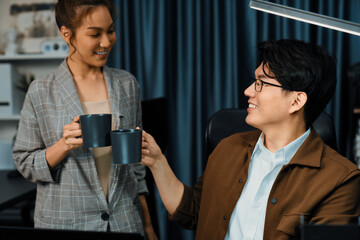 Sales managers discussing while drinking coffee cup together at over late night at home office, concept of modern working place with business report at breaking time with coworker at desk. Infobahn.