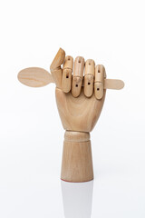 Wooden disposable spoon in a wooden hand of a mannequin on a white background.