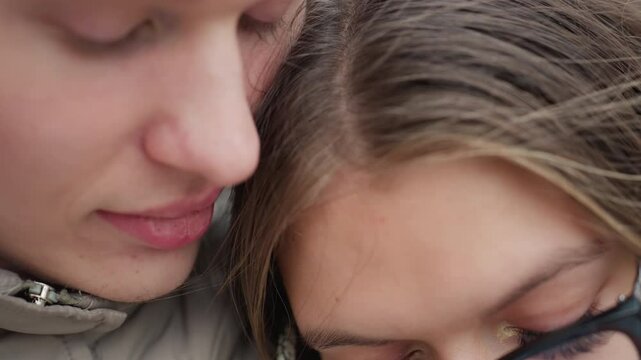 Close up romantic moment of man gently kissing woman head as she leans close in peaceful embrace, capturing tender connection and warmth between lovers with natural background