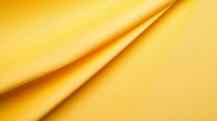 A close-up view of smooth, vibrant yellow fabric showcasing its texture and folds.