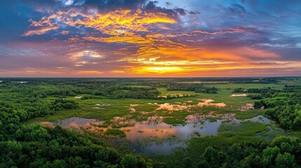 Obraz premium Aerial view of serene wetland landscape at sunset with vibrant sky reflections