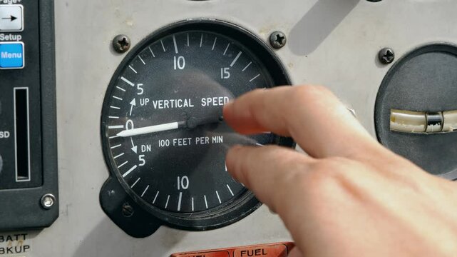 The pilot of the aircraft taps his finger on the non-working vertical speed indicator in the cockpit of the aircraft. Concept of reliability of aviation instruments