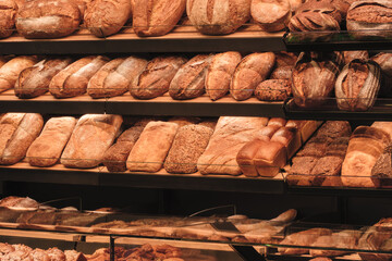 Breads on the shelf in the market or bakery.  bakery with many different types of bread on display. bread is arranged in rows and there are many different types of bread to choose from
