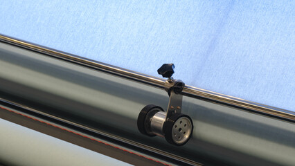 A machine is weaving a piece of fabric. The machine is made up of many parts, including a large...