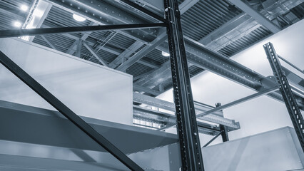A warehouse with lots of metal racks and white cardboard boxes. The beams are of different shapes and sizes, and lights shine from the metal ceiling.