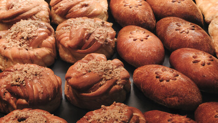 Breads on the shelf in the market or bakery. variety of pastries with different shapes and toppings. pastries are arranged in a row, with some being larger and others smaller.