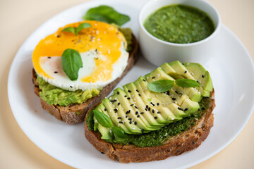 Balanced breakfast with egg, avocado and herbs. Bruschetta with sauce, egg and avocado.