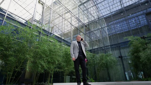 Businessman talking on the phone. Modern office atrium concept.