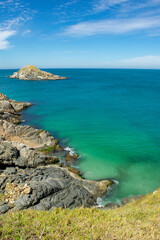 Part of Praia Grande, with beautiful blue sky, rocks, mountains with low vegetation and sea with crystal clear green waters and small islands. Near Cabo Frio, Rio de Janeiro, Brazil