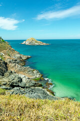 Top view of Praia Grande, with beautiful blue sky, rocks, mountains and low vegetation and sea with crystal clear green waters and small islands. Rio de Janeiro, Brazil.