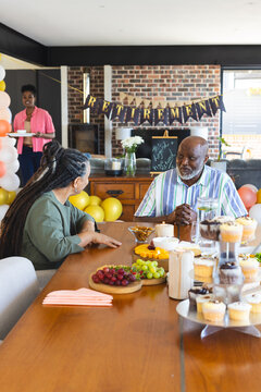 Celebrating retirement, diverse group enjoying conversation and snacks at home party