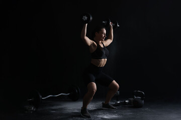 Woman training with barbells on black background