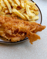 Award-winning fish and chips, featuring crispy golden fried fish with thick-cut fries, served on a rustic table. A British classic dating back to the 19th century, loved for its crispy texture.