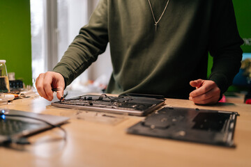 Fototapeta premium Cropped shot of electronic engineer using tweezers, fixing components on laptop motherboard, performing maintenance and troubleshooting in repair workshop. Concept of computer hardware, repairing.