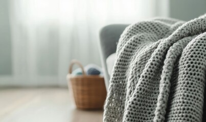 A soft gray woven blanket elegantly drapes over a modern armchair, creating a cozy, inviting atmosphere in the living room.