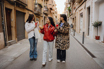 A multinational group of young women enjoying a fun moment outdoors in a city street, dressed in...
