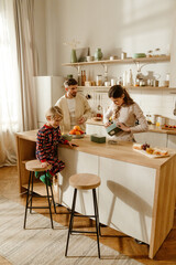 Family, mother standing and holding lunchbox while son sits next to her and father stands, in the kitchen, before going to school