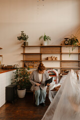 The female owner sits on a chair and holds a laptop and phone while looking down, before opening the cafe