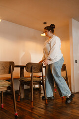 The female owner walks and looks at the table while holding her hands near the chair, preparing to open the cafe
