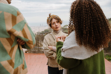Obraz premium A woman stands and listens to a female friend standing next to her while a friend stands next to them, on the street, after dinner
