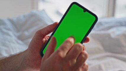 Man zooming chromakey smartphone in comfortable bed at domestic morning closeup