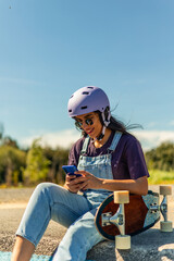 Latin skater girl using smartphone and wearing helmet in pump track © EDER