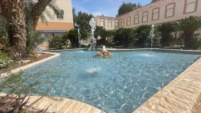 Discover a fountain with jets in a lush residence, decorated with abundant greenery. Experience the tranquility and beauty of this verdant and serene space.