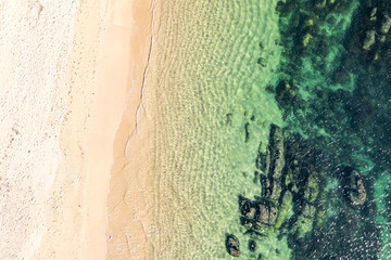 drone shot of sandy beach merging with rocky ocean floor. Aerial drone top down view. Background...